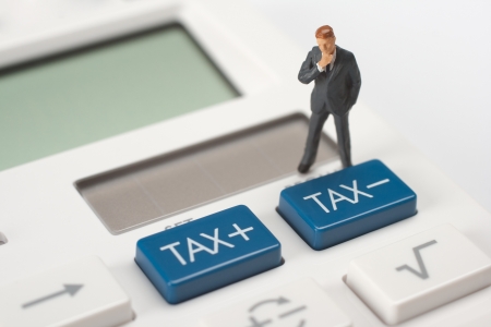 Tax concept - think figurine stand on calculator near tax buttons  の写真素材