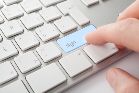 Electronic signature concept. Man press sign key on computer keyboard.の写真素材