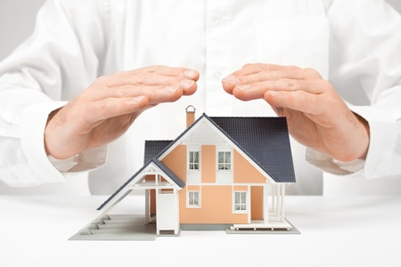 Property insurance concept - man protect model of the house.の写真素材