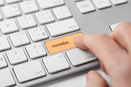Monetize on-line internet project concept. Freelancer (e-nomad, digital nomad) revenue his microbusiness startup - click on keypad monetize on keyboard.の写真素材