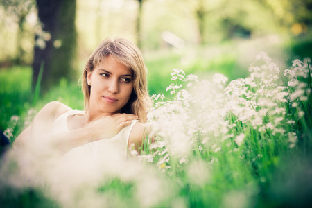 Woman relax in grass in springtime. Blurred background with bokeh.の写真素材
