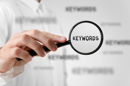 Find keywords concept. Marketing specialist looking for keywords (concept with magnifying glass).の写真素材
