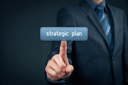 Businessman click on virtual button with text strategic plan.の写真素材