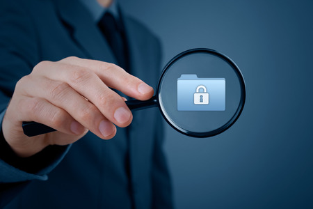 Corporate data security concept. Businessman focused on protected folder by magnifying glassの写真素材