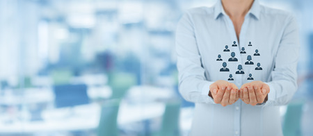 Customer care, care for employees, life insurance and marketing segmentation concepts. Protecting gesture of businesswoman or personnel and icons representing group of people. Wide banner composition wit office in background.の写真素材
