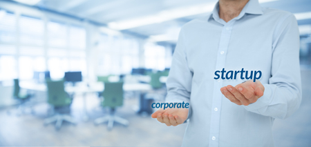 Startup versus corporate business concept. Young businessman (or employee) prefer startup company against corporation. Wide banner composition and office in background.の写真素材