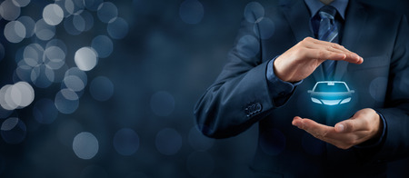 Businessman with protective gesture and icon of car. Wide banner composition and bokeh in background.の写真素材