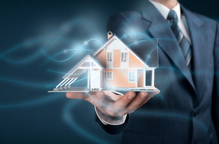 Real estate agent offer intelligent house, smart home and home automation concept. Model of the house and wireless communication represented by futuristic graphics.の写真素材