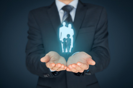 Family life insurance, family services and supporting families concepts. Businessman with protective gesture and silhouette representing young family.の写真素材
