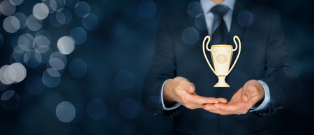 Business success, benchmarking and be number one on market concepts. Businessman hold cup representing success. Wide banner composition with bokeh in background.の写真素材