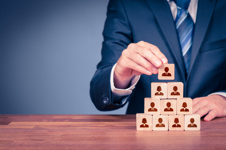Human resources, corporate hierarchy concept and multilevel marketing - recruiter complete team represented by wooden cube by one leader person (CEO) and icon.の写真素材