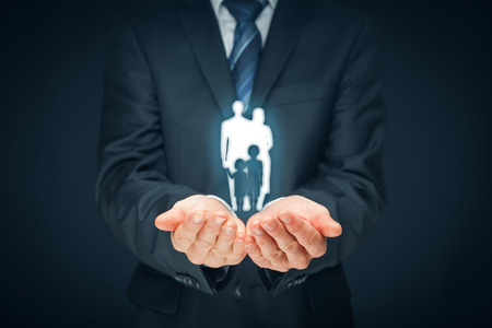 Family life insurance, family services and supporting families concepts. Businessman with protective gesture and silhouette representing young insured family.の写真素材