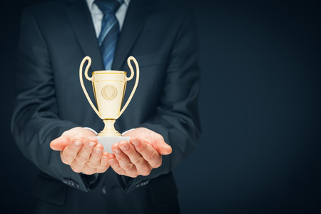 Business success, bench marking and be number one on market concepts. Businessman hold cup representing success.の写真素材