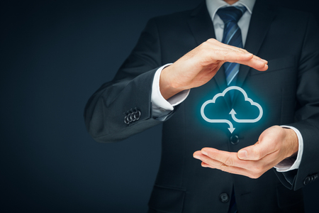 Cloud computing security concept - connect devices to cloud. Businessman or information technologist with cloud computing icon and protective gesture.の写真素材