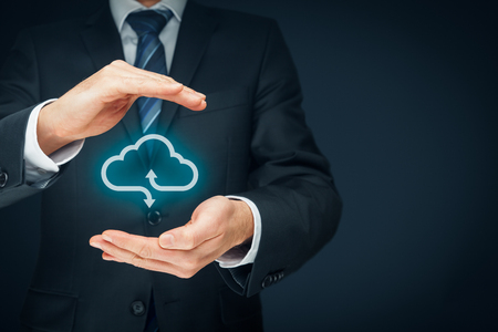 Cloud computing security concept - connect devices to cloud. Businessman or information technologist with cloud computing icon and protective gesture.の写真素材