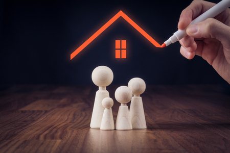 Family life and property insurance concept. Wooden figurines representing family and hand drawing house, symbol of insurance.の写真素材