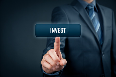 Invest concept. Investor (trader) click on button with text invest.の写真素材
