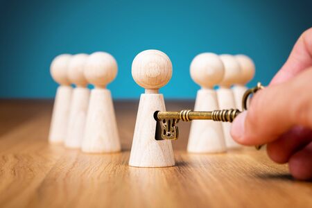 Coach unlock potential - motivation concept. Coach (manager, mentor, HR specialist) unlock leader potential and talent represented by wooden figurine and hand with key.の写真素材