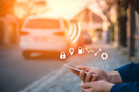 Intelligent car app on smart phone concept, intelligent vehicle and smart cars concept. Person with smart phone on street, car in background and wireless communication with car.の写真素材