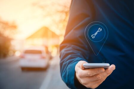 Search car service on smart phone. Smart car and new technologies in cars concept. Person with smart phone in hand walk on the sidewalk and search the nearest car service.の写真素材