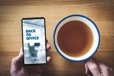 Back to office after covid-19 notification on smart phone concept. Worker read message on smart phone about office reopening after home quarantine in post covid-19 era.の写真素材