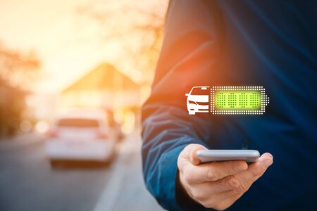Full charged electric car concept. Electric car owner is looking to battery condition of his car on smart phone app.の写真素材