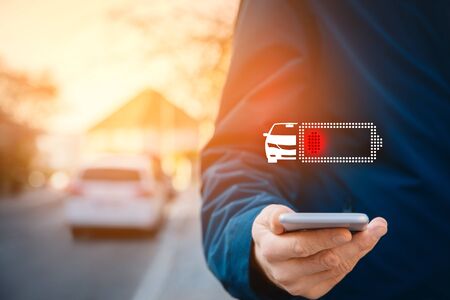 Waiting for charge of electric car concept. Electric car owner is looking to battery condition of his car on smart phone app.の写真素材