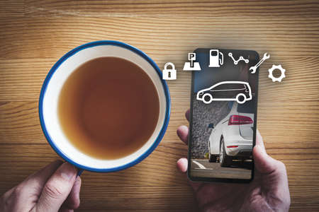 Intelligent car app on smart phone concept, intelligent vehicle and smart cars concept. Person with smart phone during breakfast, car on smart phone background.の写真素材