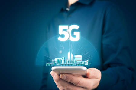 5G internet connection on smart phone concept. Person hold smartphone with 5G broadband cellular network around smart city.の写真素材
