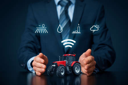 Intelligent agriculture concept with businessman, tractor and icons symbolizing data about fields, soil moisture, crop yield (productivity and efficiency) and weather forecast.の写真素材