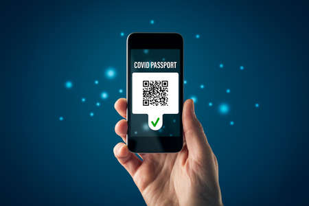 Covid passport certificate (covidpass) concept with smart phone. Person looking on personal covid passport with fictitious QR code on smart phone. Post-covid era concept.の写真素材