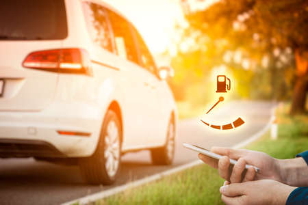 No fuel in intelligent car concept. Person with smart phone, car in background and wireless communication with car.の写真素材
