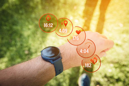 Runner uses smart watch during smart training to improve physical fitness. Actual data about duration, distance, heart rate, pace and cadence. Modern sport concept with wearable.の写真素材