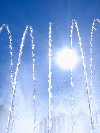 Fountain jets against sunlight and blue skyの写真素材