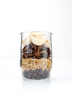 Garlic, star anise,coriander seed and coffee grains set up in glass jar on white background, seasoning ingredients for cooking.の写真素材