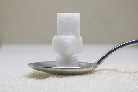 Pure refined sugar and sugar cubes on spoon. Sweet food ingredient, the diet health risks related to diabetes and calorie intake.の写真素材