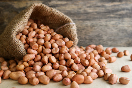 Peanuts in hemp sack on wooden background. Peanuts are rich in energy and anti-ageing. Nuts can...