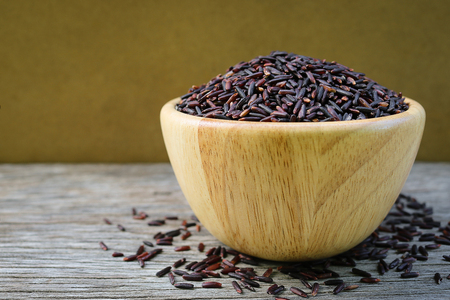 Riceberry in wooden bowl on rusitc wood background. Riceberry  Rice is the new variety of rice that has been bred in Thailand. The rice is deep purple in colour is rich in many antioxidant and many health benefitsの写真素材
