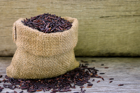 Riceberry rice in hemp sack on wooden background. Riceberry  Rice is the new variety of rice that has been bred in Thailand. The rice is deep purple in colour is rich in many antioxidant and many health benefitsの写真素材