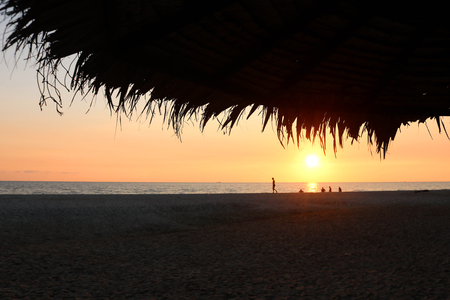 Beautiful tropical sunset summer beach with white sand and thatched roof. Sunset view under the thatched hut.の写真素材