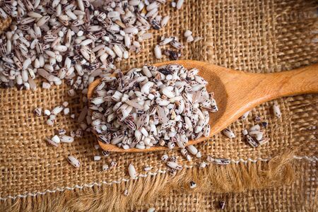 Organic black sticky rice in wooden spoons on sack. Purple rice contains more antioxidant compounds than white rice and they help protect the body's cells from harmful free radicals.の写真素材