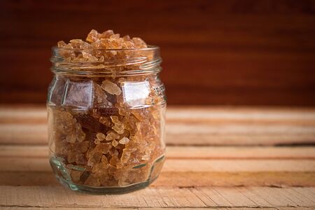 Natural rock sugar in glass bottle on rustic table. Many healthy benefits of consuming natural sugar as it contains numerous vitamins, minerals and amino acid.の写真素材