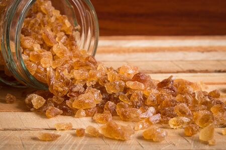 Natural rock sugar in glass bottle on rustic table. Many healthy benefits of consuming natural sugar as it contains numerous vitamins, minerals and amino acid.の写真素材