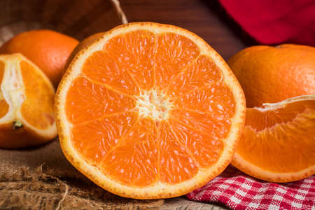 Half and whole fresh oranges on wooden table. Oranges are an excellent source of fiber and vitamin...