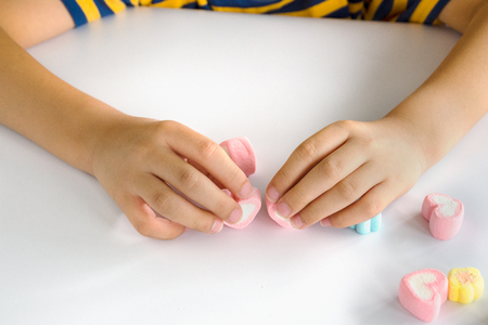 Child hands play jellys on white tableの写真素材