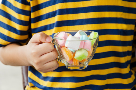 Child hand on jellys in cup on white backgroundの写真素材