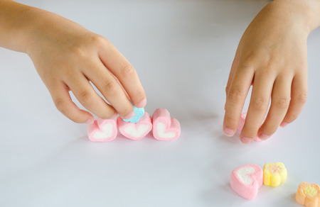 Child hands play jellys on white tableの写真素材