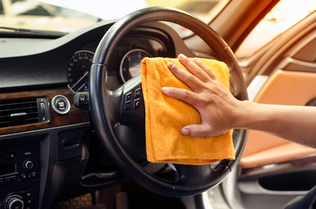 Hand with violet microfiber cloth cleaning interior car.の写真素材