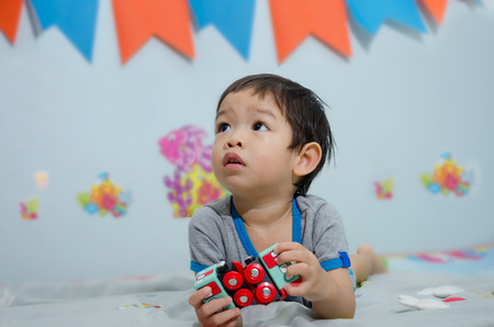 Asian Child Lay Down On Floor And Playing Wood Trian Toyの写真素材