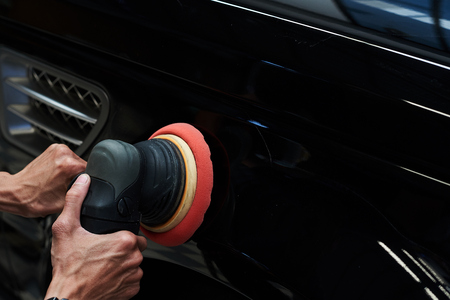 Hands with daul action polisher. polishing on car surface. foam pad in blur motion from vibration of polisher machineの写真素材